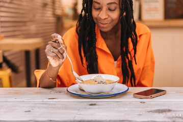 A smiling African American woman eating a healthy vegetable soup. Healthy food concept