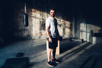 Determined sportsman standing at gym with fitness equipment