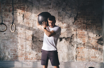 Strong male athlete exercising with medicine ball at gym