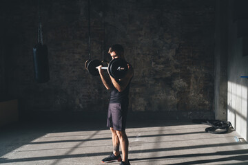 Fototapeta na wymiar Slim sportsman exercising with barbell