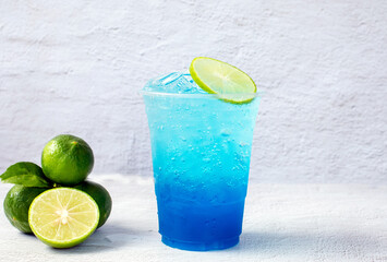 Blue Hawaiian drink in a plastic glass and lime on white background