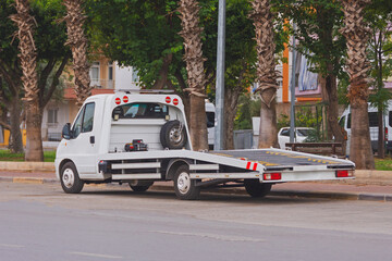 Empty tow truck transporter parked on the side of the road.