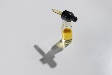 CBD oil in a clear, glass container with a dropper lid, isolated on a white background, to...
