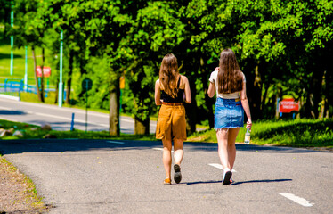 Two girlfriends walk along a path in the Park
