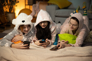 Happy female friends having good time at pajama party in the bedroom. friendship, people, pajama party, entertainment and junk food concept