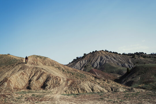 Motorcyclist riding pit bike cross enduro motorcycle over the hills of canyons mountains