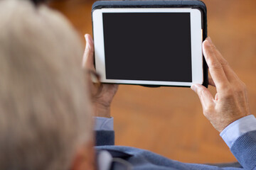 Businessman using tablet with blank screen. Over shoulder view of unrecognizable man watching webinar. Digital device concept