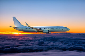 Naklejka na ściany i meble White passenger airliner flies in the sunset sky