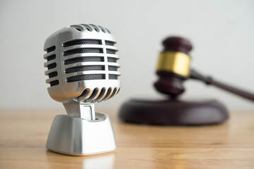 Retro microphone with hammer judge gavel on wooden table and white wall background copy space. Law against propaganda, fake news, misinformation concept.