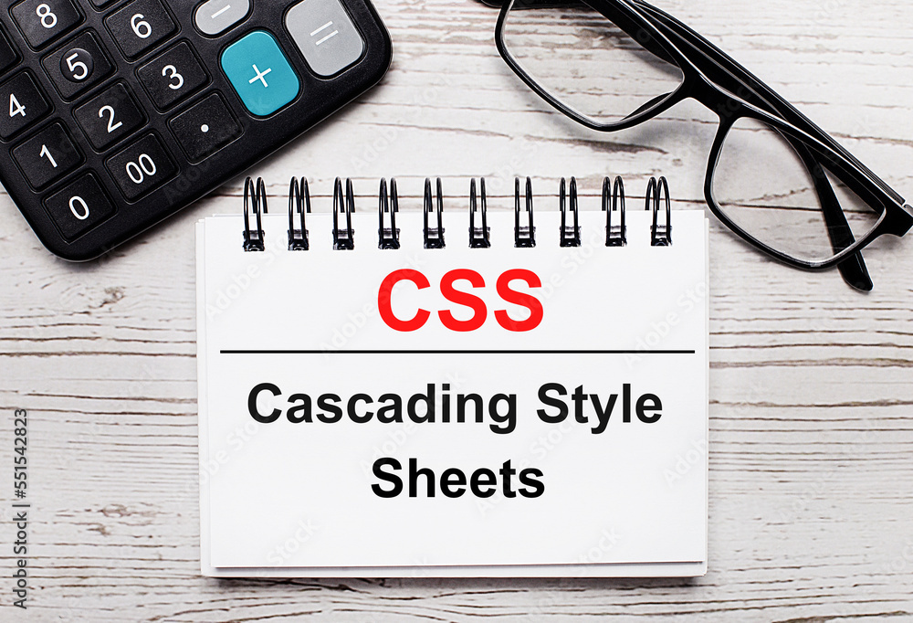 Poster on a light wooden table calculator, glasses and a blank notepad with the text css cascading style sh