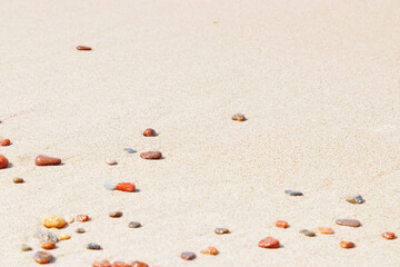 Natural stones amber yellow colored on beige sand. Aesthetic minimal nature scene with pebble stones on fine sandy background. Summer vacation or relaxation concept, selective focus