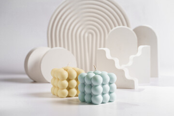 an off-white and blue bubble candle in front of white props for product photography on white...