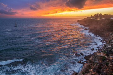 Red colorful sunset and vivid dramatic sky at rocky shore of the Atlantic ocean. © volff