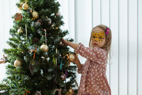 Girl with face painted decorating Christmas tree at home