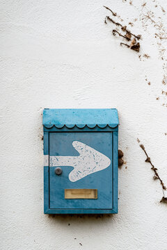 Metal mailbox with arrow on white wall
