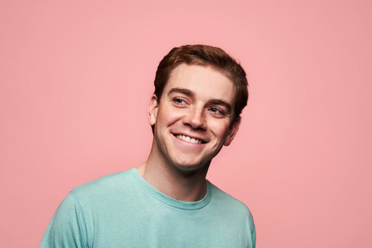 Glad young red hair man standing against pink background