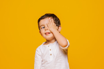 Cute little boy looking away and covering face