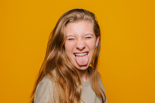 Cheerful young with brackets sticking out tongue