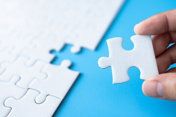 Closeup hand of woman connecting jigsaw puzzle, Business solutions, success and strategy concept.