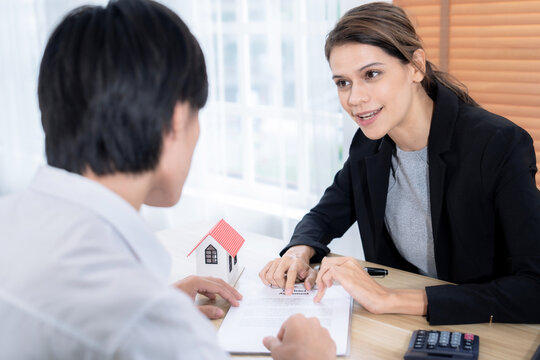 The real estate agent talks to the client about the terms of the home purchase agreement and asks the client to sign the paperwork to complete the sale.