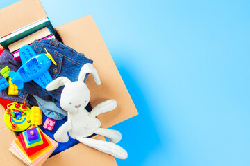 Donations box with kid toys, books, clothing for charity on blue background. Top view. Donations...