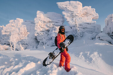 Woman with snowboard on  sunny snowy slope with beautiful mountain rocks valley view. Sports outdoor lifestyle, sunset pink colors