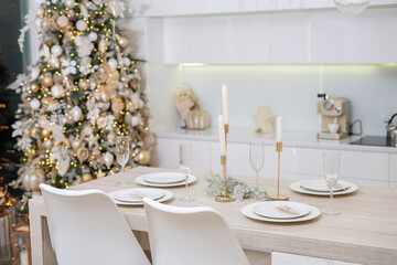 Christmas decor. Bright interior of white kitchen with decorated Christmas tree, garlands and Christmas wreaths.