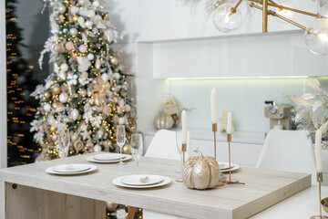 Christmas decor. Bright interior of white kitchen with decorated Christmas tree, garlands and Christmas wreaths.