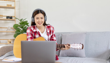 Woman artist playing the guitar and live or stream on laptop in the living room, Relaxation with...