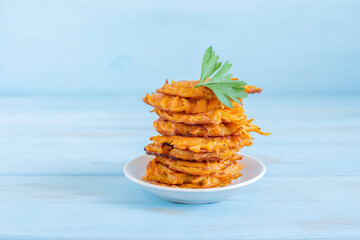 Batata Latkes or Sweet Potato Fritters for Jewish holiday Hanukkah on blue wooden background.