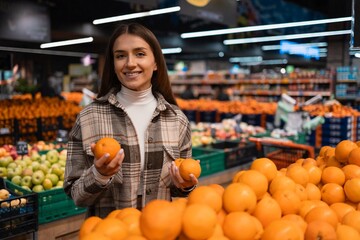 Portrait of happy female customer of a grocery store with oranges in her hands