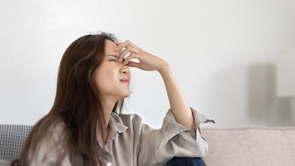 Fototapeta premium Stressed woman holding her temples with severe problems in her life, Family problems, Pressure from work, Poor financial, Despair in life, discouraged and deeply saddened, Panic attacks.