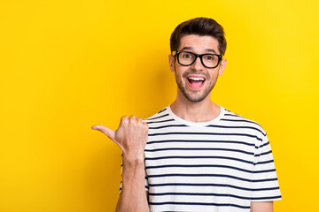 Photo of astonished cheerful man open mouth indicate thumb finger empty space isolated on yellow color background