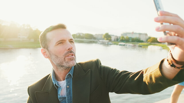 Close Up, Man Makes Selfie On Mobile Phone On The Embankment Of The River. Backlight