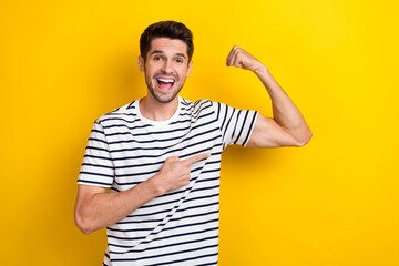 Photo of crazy positive man toothy smile indicate finger show arm flex biceps isolated on yellow color background