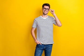 Photo of cheerful young man hand touch glasses toothy smile isolated on yellow color background