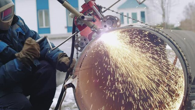 Welder cuts large diameter metal pipe and sparks fly. Industrial pipe cutting device. Stabilized video. Authentic workflow..
