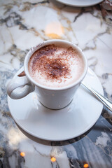 Hot chocolate or coffee in a white cup in the middle of a table on the terrace of a Parisian café