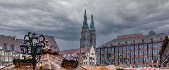 Obraz premium Blick über die Dächer des Christkindlmarktes in Nürnberg, am Nachmittag bei regen, zu den Türmen der Sebalduskirche