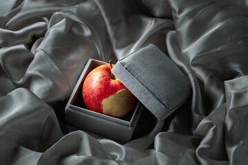 Bitten apple in a gray gift box.