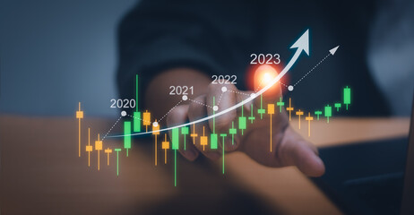 Fototapeta premium Businessman or trader touching a virtual hologram stock chart. Showing growth 2023, investment ideas in the stock market or digital assets, funds, financial business exchange analysis