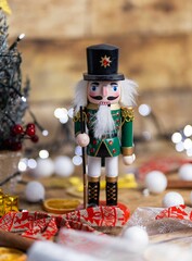 Obraz premium Vertical shot of a wooden nutcracker toy on the table with Christmas decorations