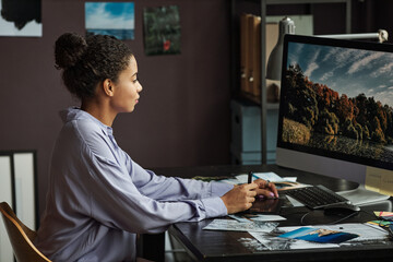 Young female photographer editing photos of nature on computer