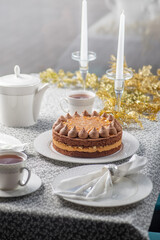 Festive served Christmas table with cake. Family tea party for christmas and new year. Dining table decorated with gold tinsel
