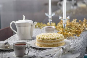 Festive served Christmas table with cake. Family tea party for christmas and new year. Dining table decorated with gold tinsel and candles