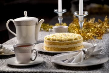 Festive served Christmas table with cake. Family tea party for christmas and new year. Dining table decorated with gold tinsel