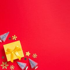Christmas border with golden gift box with mini Christmas trees and baubles on bright red background