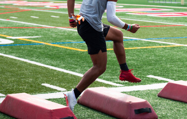 Young athlete running over soft red barriers at football summer camp