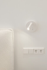Bedside white LED wall lamp illuminating. Creative modern wall light source in bedroom. White...