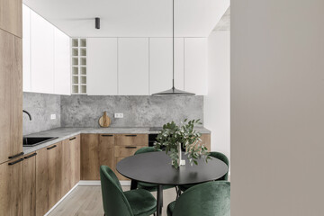 Modern minimalistic kitchen and dining room interior with wooden and white surfaces, green chairs...